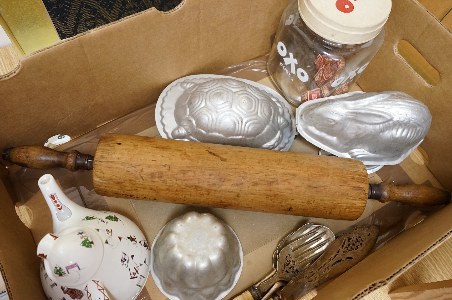 A collection of Kitchenalia, including a Wade novelty teapot, a large wooden rolling pin, jelly moulds, etc.